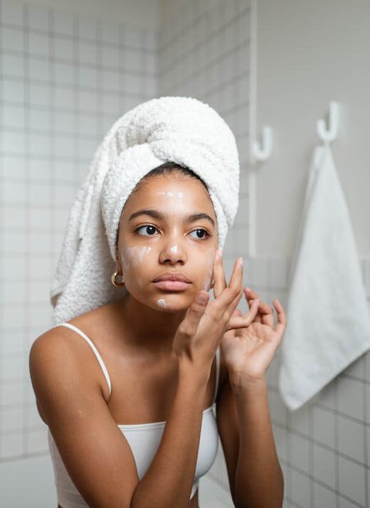 A woman applies sunscreen onto her face