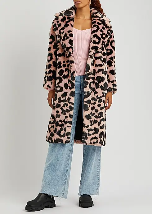 A woman wears a long faux fur animal print coat by JAKKE.
