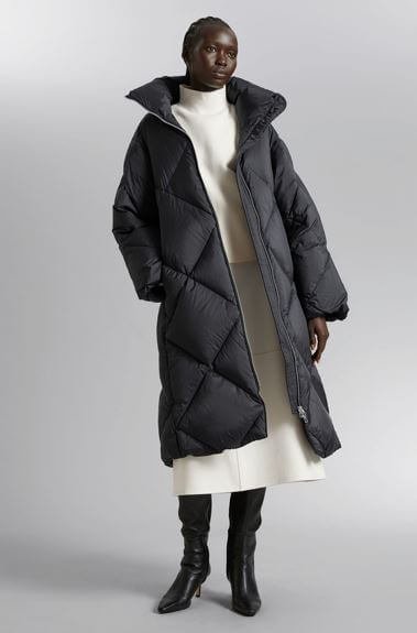 A woman wears an oversized padded puffer coat by & Other Stories.