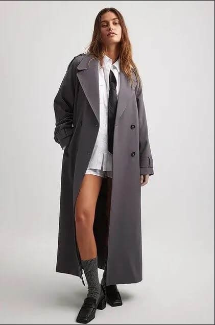 Autumn coats. A woman wears a long grey trench coat by NA-KD.