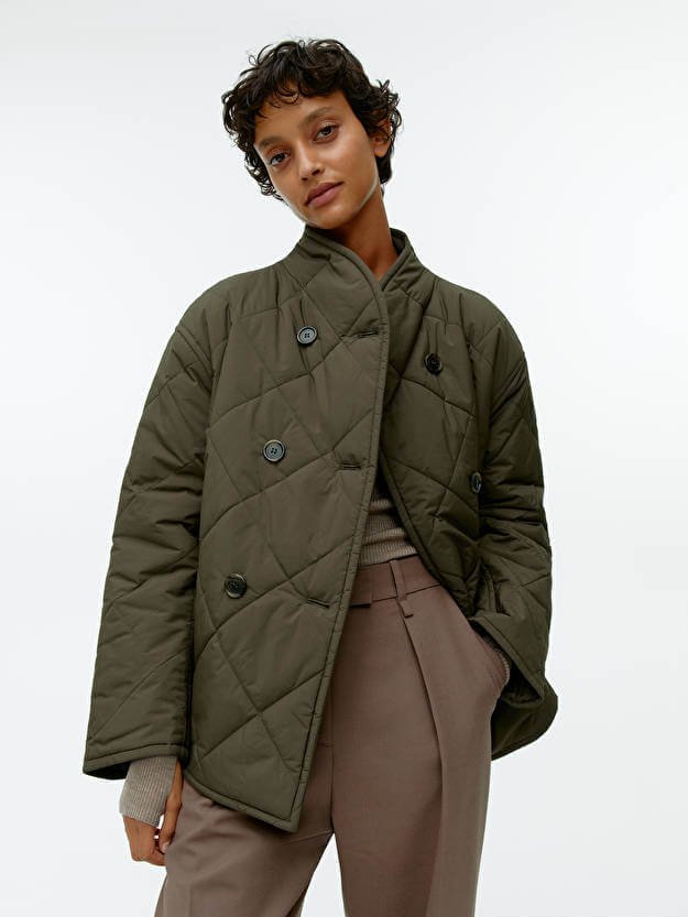 Autumn coats, a woman wears a quilted shawl-collar jacket by ARKET.