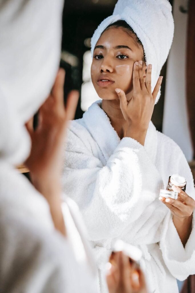 A woman applies cream to her face.