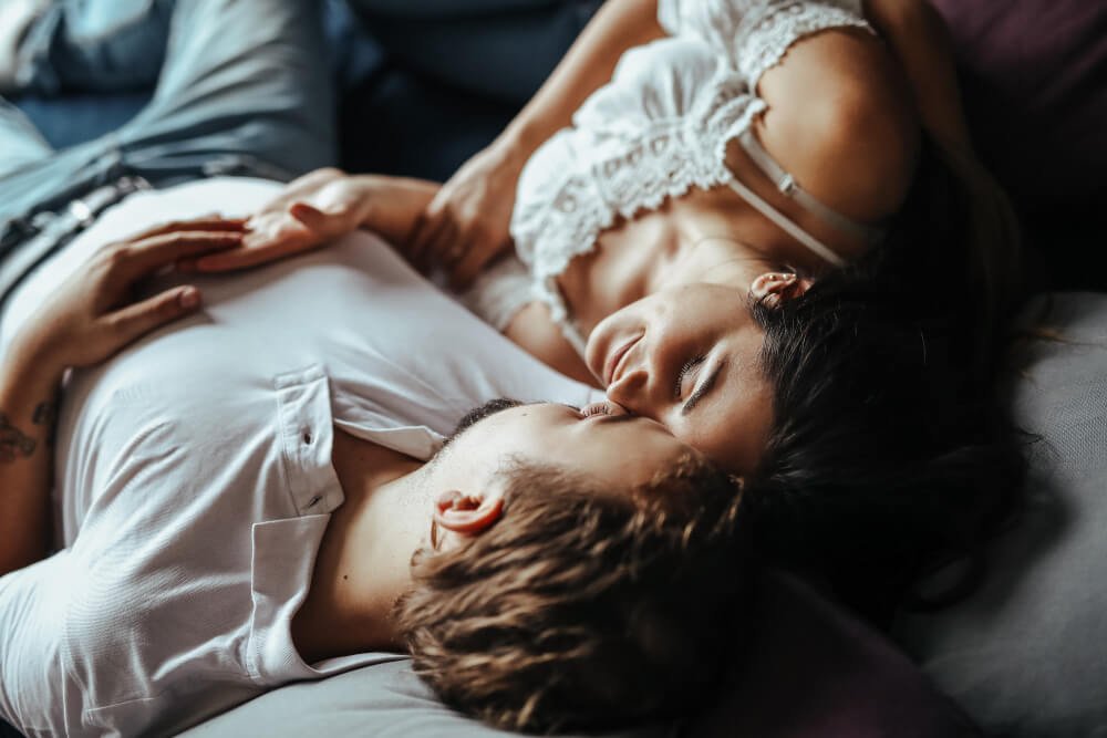 A couple lie on a bed together