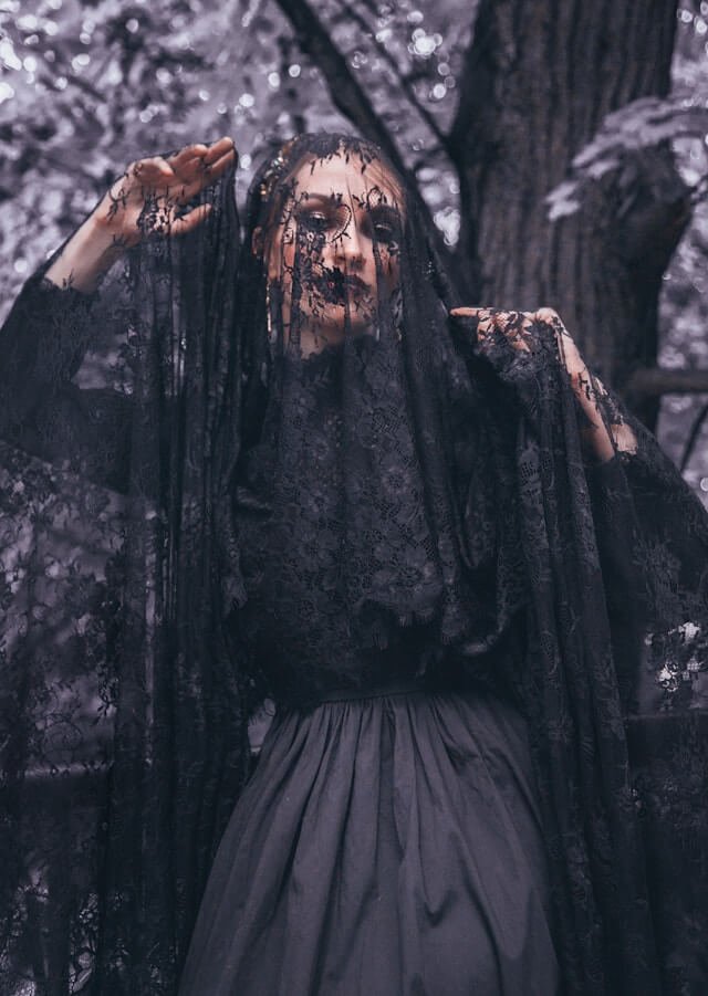 A woman is dressed up in a gothic bride Halloween costume