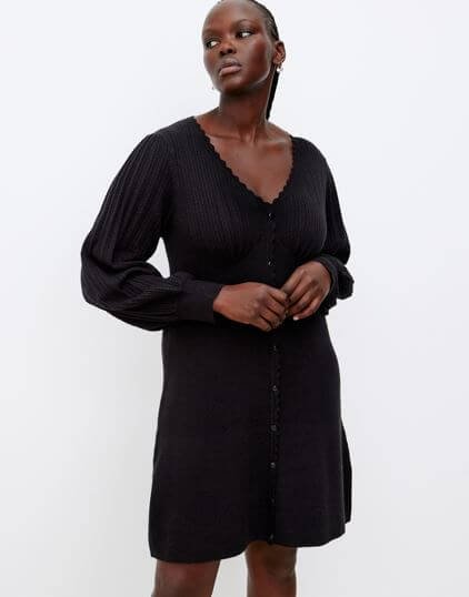 A model wears a black mini dress with long sleeves.