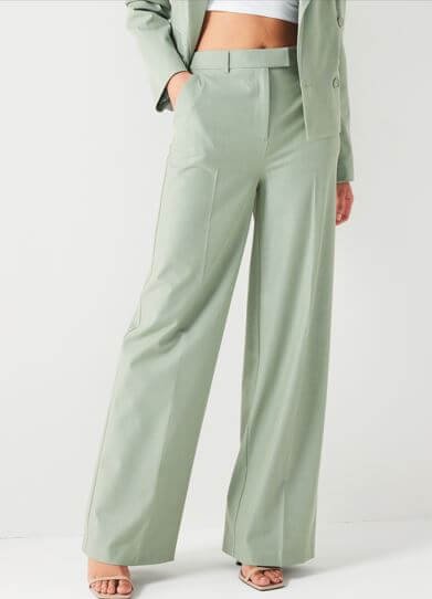 A woman wears a pair of mint coloured wide-legged tailored trousers.