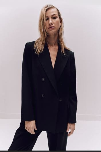 A woman wears a black blazer and matching black trousers