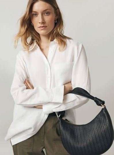 A blonde woman wears a white linen shirt.