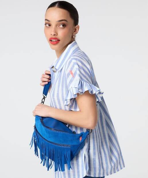 A woman wear a blue fringe bag and a blue and white stripe shirt