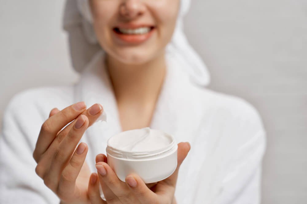 A woman holds a pot of face moisturiser