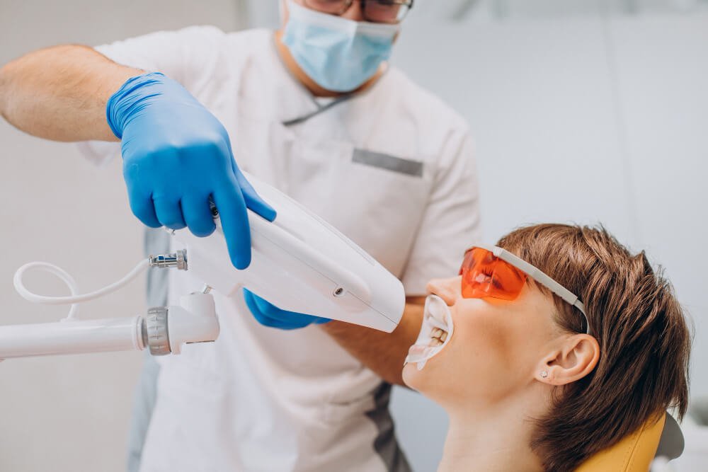 A woman is getting her teeth whitened by a dentist