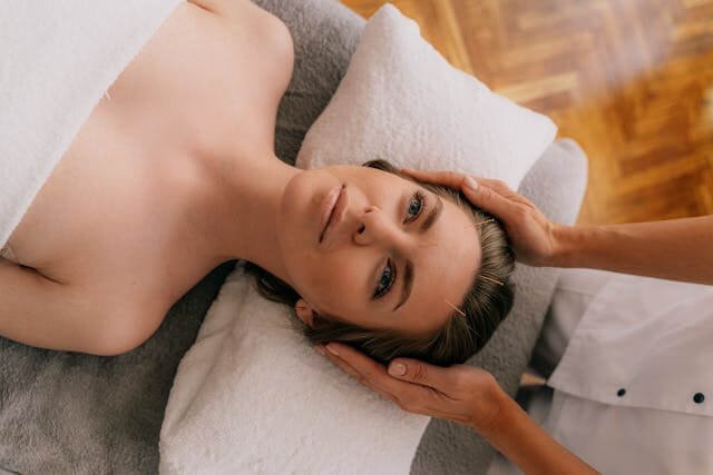 A woman lying on a bed is getting facial acupuncture