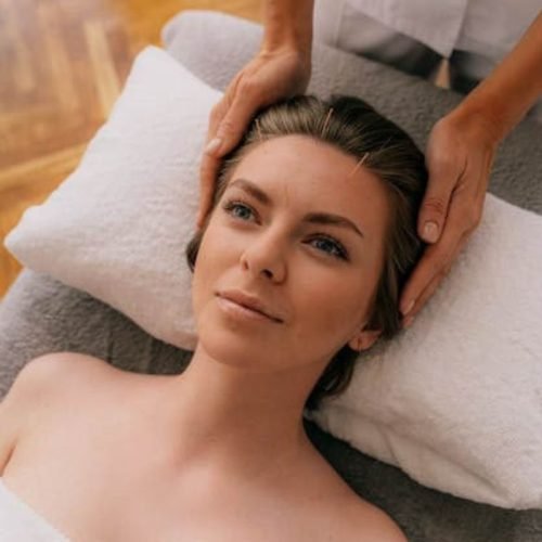 A woman is getting facial acupuncture