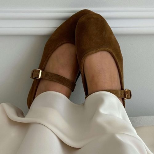 How to create a shoe capsule wardrobe: A woman wears a pair of brown Mary Jane ballet flats.