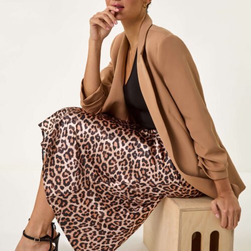 A model is wearing a satin leopard skirt and a blazer, and strappy heels
