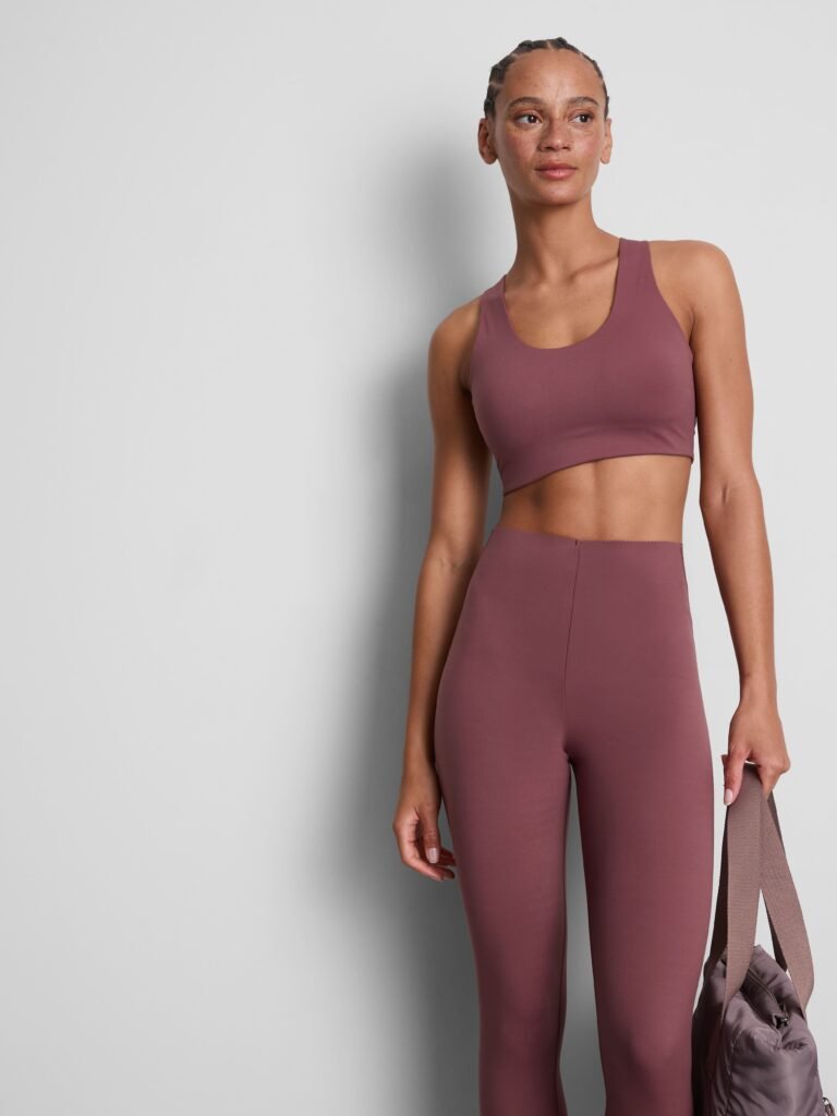 A model wears a gym crop top and matching leggings in a plum colour.
