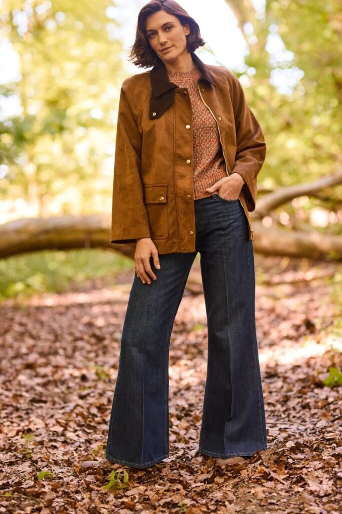 How to style wide leg jeans in Winter.
a model with short brown hair wears dark blue wide leg jeans with a pleat down the front, a peach wool jumper and a brown suede jacket.